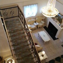 リージェンス・ウェディングマナーハウスの画像｜挙式会場2階から1階を見下ろす
花柄の絨毯の階段に豪華なシャンデリア