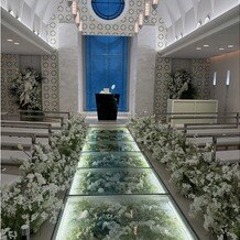 THE MARCUS SQUARE KOBE　（ザ マーカススクエア 神戸）の写真｜バージンロードの花やウエディングドレスが映える背景のブルーが素敵！
天気にも左右されない挙式会場！