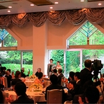 千里阪急ホテル　ＣＬＡＳＳＩＣ ＧＡＲＤＥＮ：大きな窓の外に緑が広がる爽やかな雰囲気のパーティ会場。サプライズのガーデン入場でゲストの視線を集中