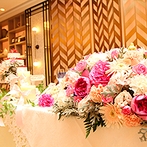 ホテルモントレ ラ・スール大阪：洗練された幾何学模様が彩る、リニューアルしたての披露宴会場。花嫁の幸せが薫りたつようなピンクの装花も