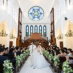 アルカンシエル luxe mariage大阪：輝くステンドグラスをバックに誓う人前式。参加型の結婚証明書やオリジナルの誓いの言葉でふたりらしく