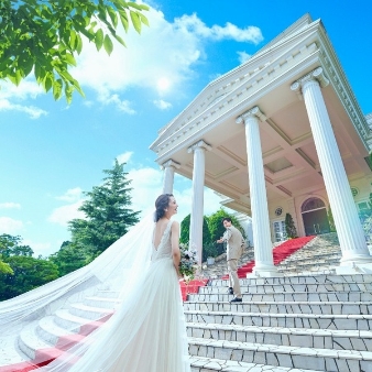 ベイサイド迎賓館　長崎:【最大20万円特典】嬉しい特典付きプラン★27年2月~27年3月に結婚式実施の方へ:【喧噪離れた非日常へご招待】JR長崎駅から車で10分、女神大橋×長崎湾×稲佐山の贅沢な眺めを独占する海辺のリゾート邸宅がハレの日の舞台。送迎バスのサービスもあるから長崎県内のゲストはもちろん、遠方からも迷わずお越し頂けると好評です。白亜の凱旋門の先には選べる二つの邸宅があり【1組で貸切】にして大切なゲストと特別な1日をお過ごし頂けます。海外リゾートのようなスタイリッシュなプール付き邸宅【ヴィクトリアハウス】と、チャペルへと続く大階段がフォトジェニックな邸宅【ホワイトハウス】。どちらにも絶景のオーシャンビューチャペルがあり、水平線に続くバージンロードとガラス越しに降り注ぐ自然の光に包まれて、開放的なリゾート挙式が叶います。「１次会はヴィクトリアハウス、２次会はホワイトハウスで。」そんな欲張りな使い方もできるのもベイサイド迎賓館の自慢です。【1組貸切】ウエディングの特別感を是非ご体感ください。