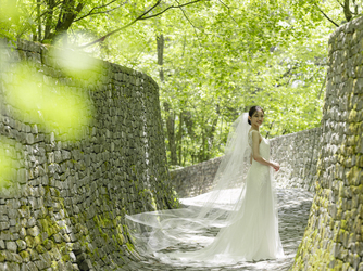 石の教会 内村鑑三記念堂：ドレス姿が一層美しく映える石畳の回廊。清らかな緑と石が調和する風景が、心を穏やかにしてくれる。