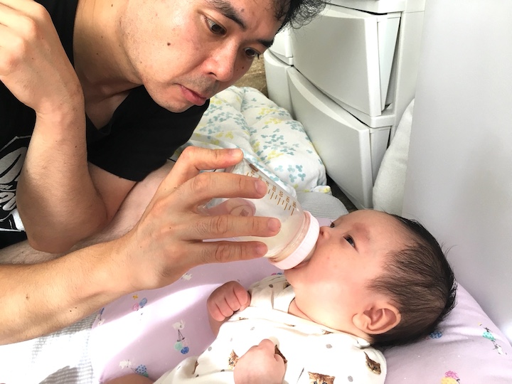 子どもに哺乳瓶のミルクを与える夫