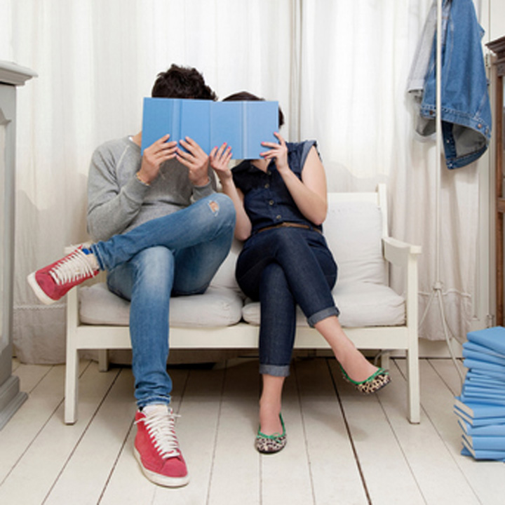 部屋の中で一緒に本を読みながら相談する夫婦