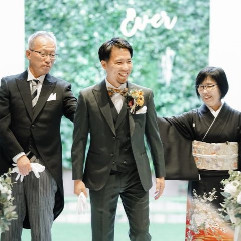 画像：父母とセレモニーを済ませ親子三人笑顔で並ぶ新郎