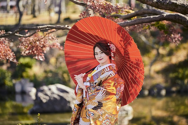 京都の町中で番傘さしてほほえむ和装姿の花嫁